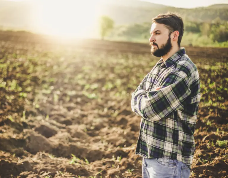 junger Landwirt steht nachdenklich auf einem Feld