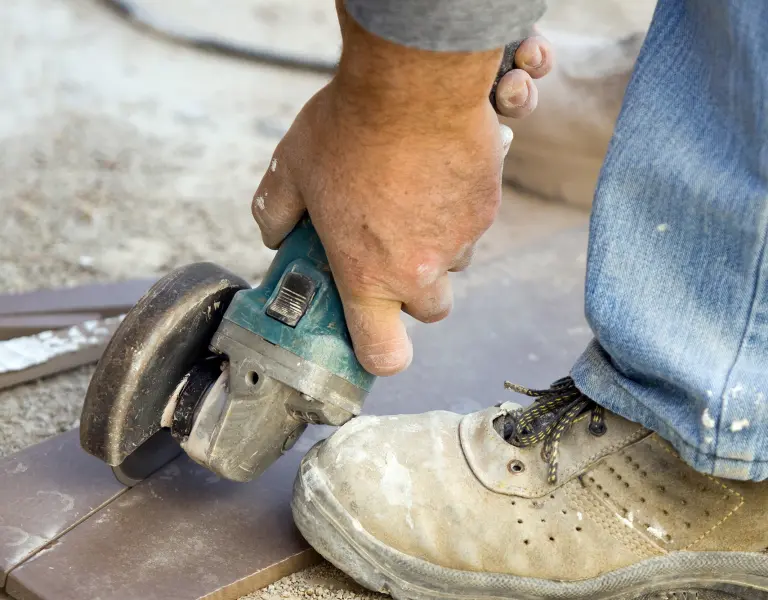 Flex schneidet auf Baustelle knapp neben einem Fuß