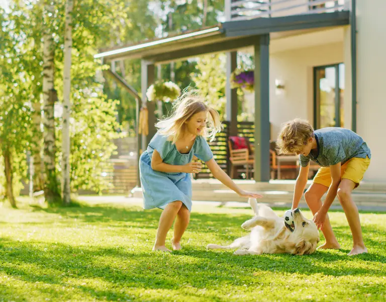 Mutter und Sohn spielen mit Hund im Garten