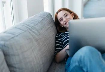 Frau am Sofa mit Laptop
