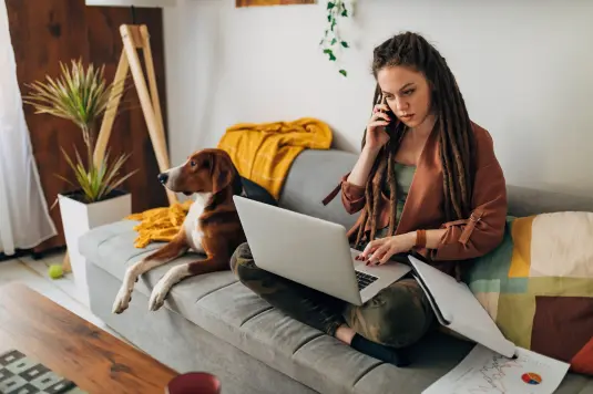 Frau mit laptop und Hund die telefoniert