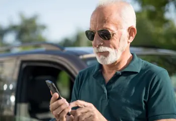 weißhaariger Mann mit Handy in der Hand