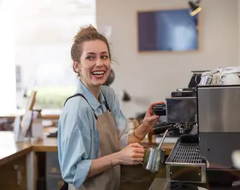 Junge Frau macht einen Kaffee im Bistro