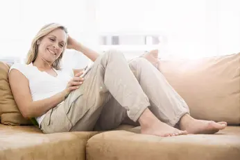 Frau sitzt nachdenkend am Sofa