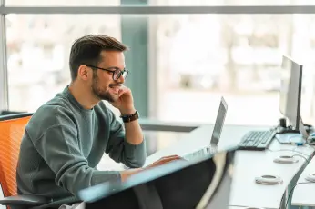 Mann sitzt am Schreibtisch vor PC