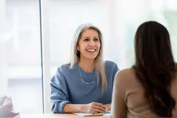 Zwei Frauen sitzen gegenüber und sprechen miteinander