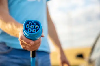 Hand die einen Ladestecker für E-Auto hält