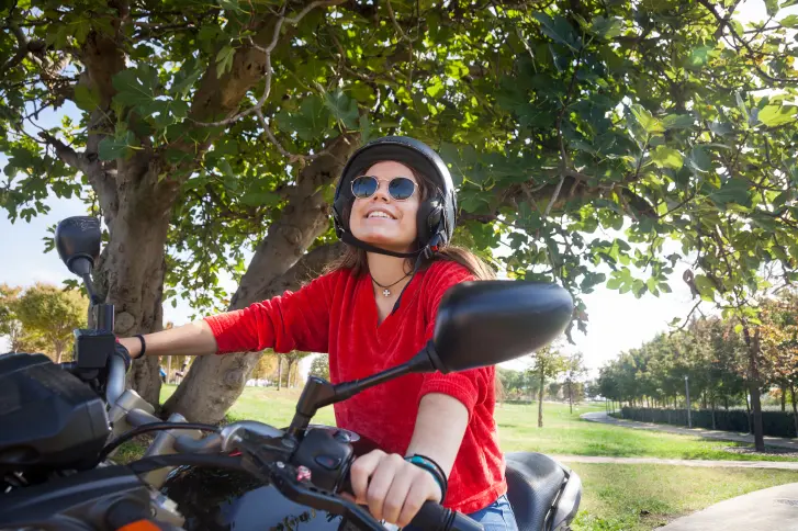 junge Frau auf Motorrad glücklich über Kfz-Hatpflichtversicherung