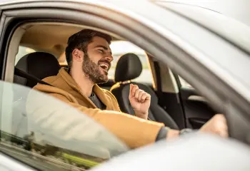 Mann sitzt im Auto und singt
