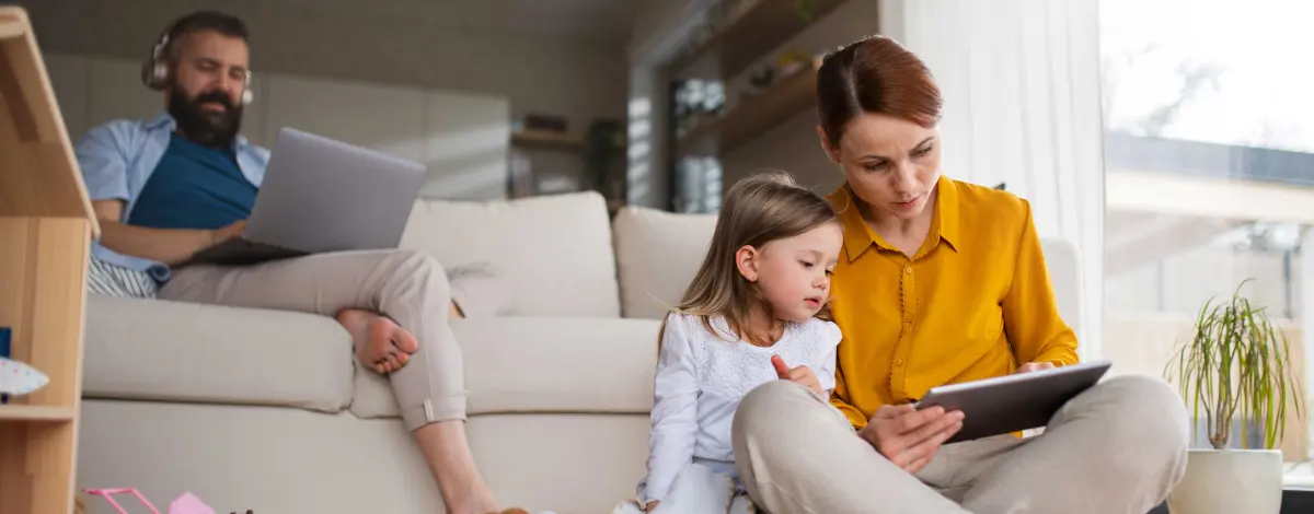 Familie sitzt am Sofa und schaut Tablett