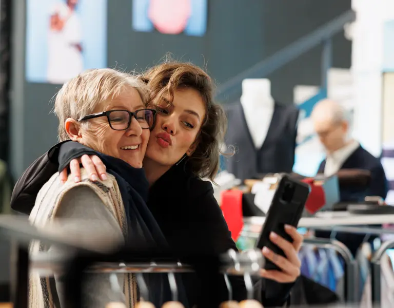 Ältere Frau und jüngere Frau posieren für ein Selfie beim Einkauf