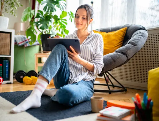 junge Frau sitzend in Wohnung am Tablet